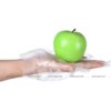 یک سیب سبز در کف دستی که دستکش پلاستیکی پوشیده