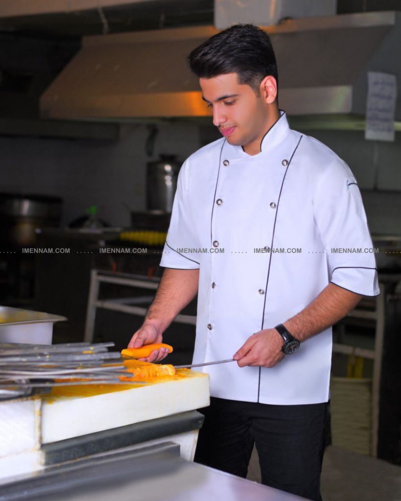 جوانی با لباس سرآشپز شایان سفید در داخل آشپزخانه یک چاقو و یک سیخ جوجه در دستانش