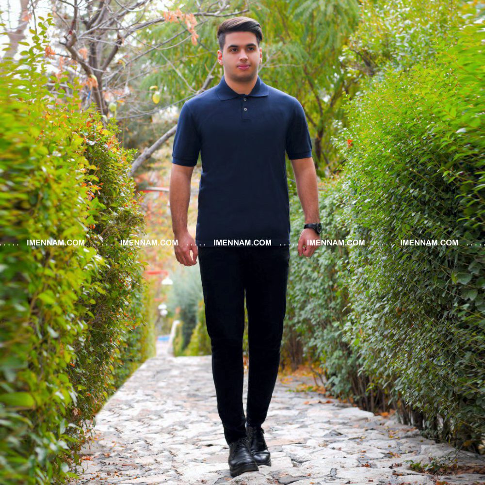 تیشرت جودون یقه دار 20 مردی با تیشرت جودون یقه دار سرمه ای در حال قدم زدن در فضای سبز