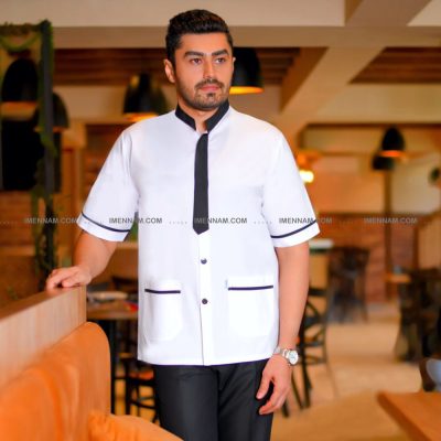 مردی لباس آشپزی کراواتی ایستاده و یک دست روی کانتر